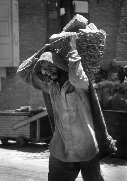 Kashmir - ragged man carries bricks in basket