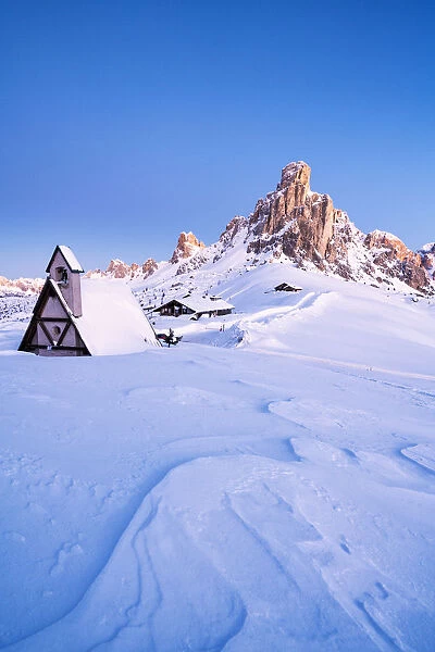 Dusk on the alpine chalet covered with snow with Ra Gusela in background, Giau Pass