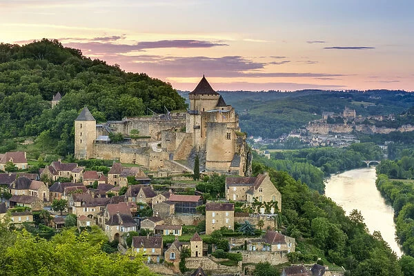 Chateau de Castelnaud castle and village over Dordogne River valley at sunset