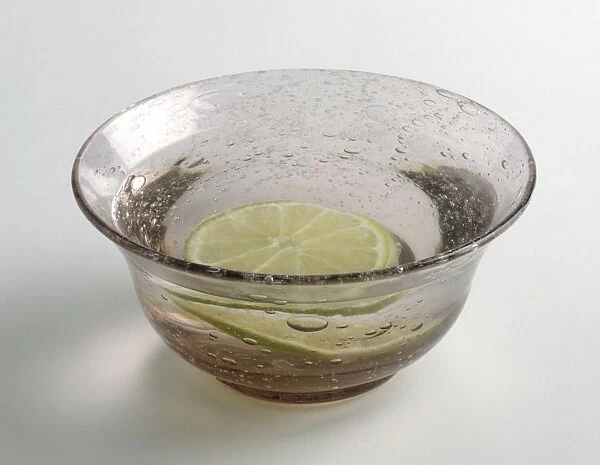 A finger bowl containing water and slice of lime