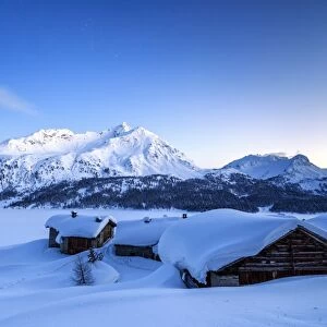The blue hour leaving its place to the night over some scattered huts in Spluga by the Maloja Pass, Graubunden, Swiss Alps, Switzerland, Europe