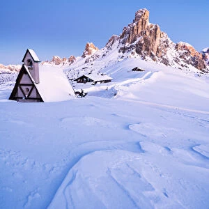 Dusk on the alpine chalet covered with snow with Ra Gusela in background, Giau Pass