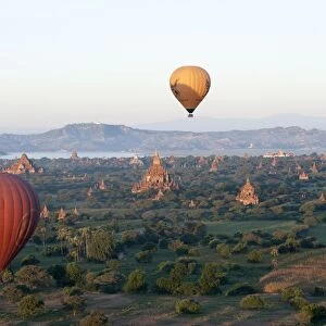 Hot air balloons flying over the terracotta temples of Bagan with the Irrawaddy river