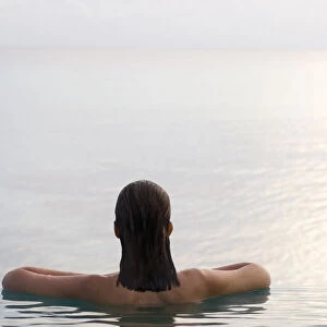 Woman relaxing in infinity pool. Rangiroa, Tuamotu Archipelago, French Polynesia. (MR)