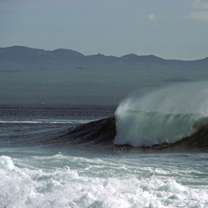 Spume and spindrift from a breaking wave with Santa Cruz Island in background. North Seymour Island, Galapagos Islands