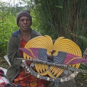 Lady selling wooden carved plaque of Papua New Guinea in design of national emblem