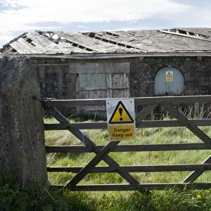 Danger, Keep out sign on gate and derelict farm building, Lancashire, England, April
