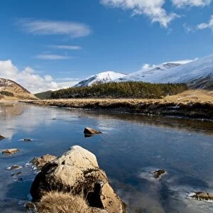 View of river flowing through valley with snow covered mountains, River Findhorn, Findhorn Valley