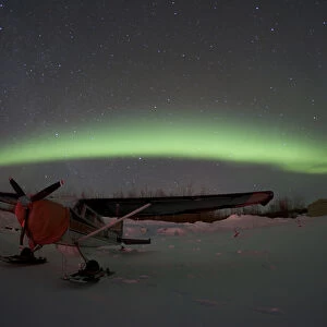 USA, Alasaka, Bettles. An airplane waits out the night beneath the northern lights