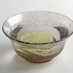 A finger bowl containing water and slice of lime