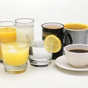 Mugs and cup of tea and coffee next to glasses of water, milk and fruit juice