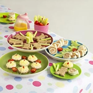 Plates of finger food on table including tuna sandwiches, cheese open sandwiches, biscuits, and cucumbers sticks