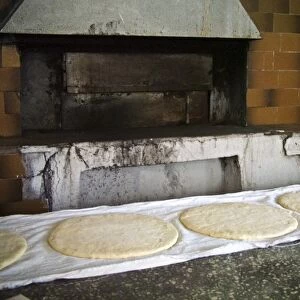 Large round flat loaves of bread rising on clean cloths on counter of quayside bakery