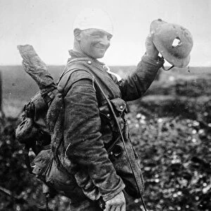 British soldier with bandaged head shows the steel helmet that saved his life