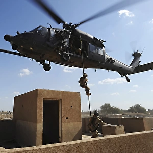 A U. S. Air Force Pararescuemen fast ropes from an HH-60 Pavehawk helicopter