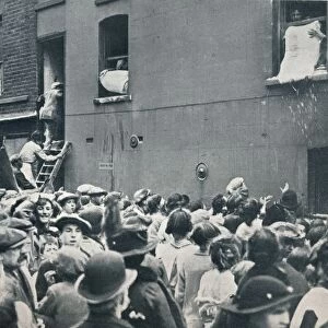Crowd watching the looting of a German house in Poplar, c1914