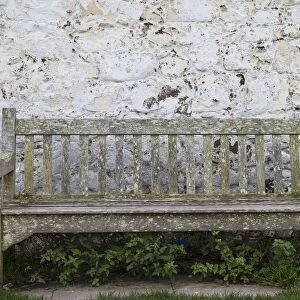 A Wooden Bench With Peeling Paint Against A White Wall; Northumberland, England
