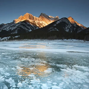 Mountains and frozen gas bubbles beneath surface of frozen lake, Abraham Lake, Canadian Rockies