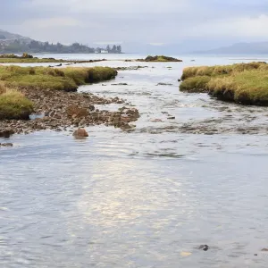 View of meandering river flowing through grassland with hills at background, Isle of Mull View of meandering river flowing through grassland with hills at background, Isle of Mull