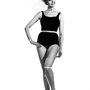 Reveille Fashions. Mannequin modeling a one piece swimming costume with a tape measure