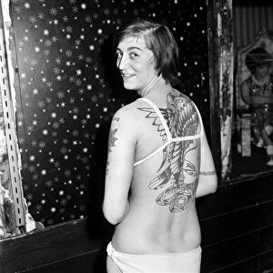 Woman with tattoos posing at her home showing off her body art