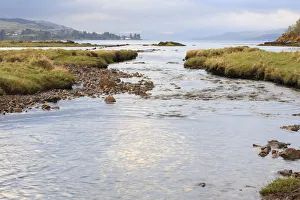 View of meandering river flowing through grassland with hills at background, Isle of Mull